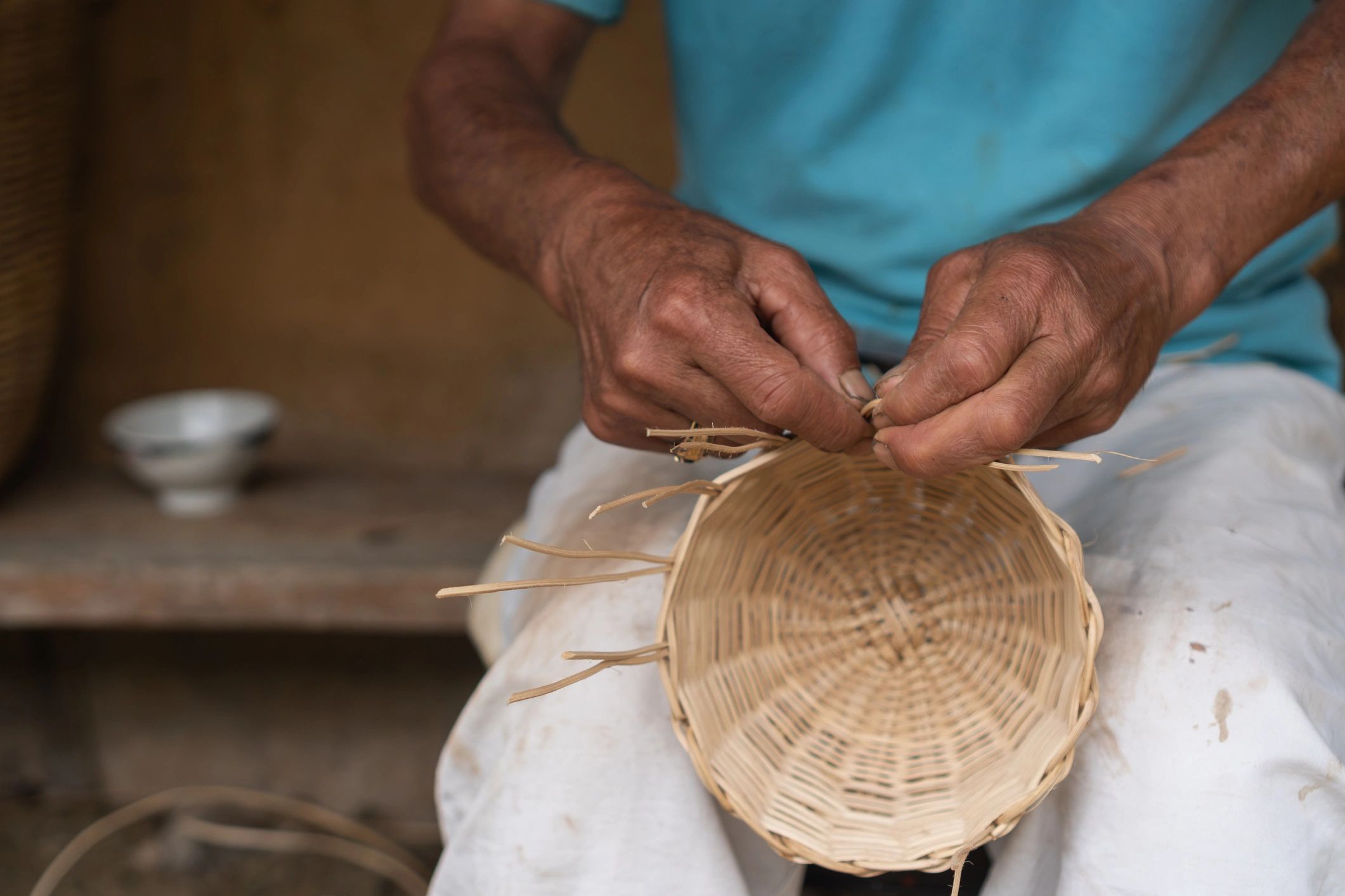 Close-up of an artisan weaving a wicker basket by hand