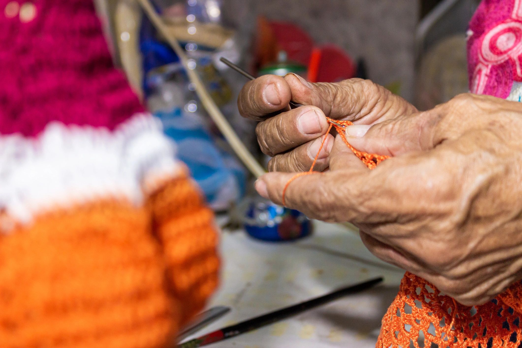 Hands of an artisan weaving orange wool in a workshop in Colombia